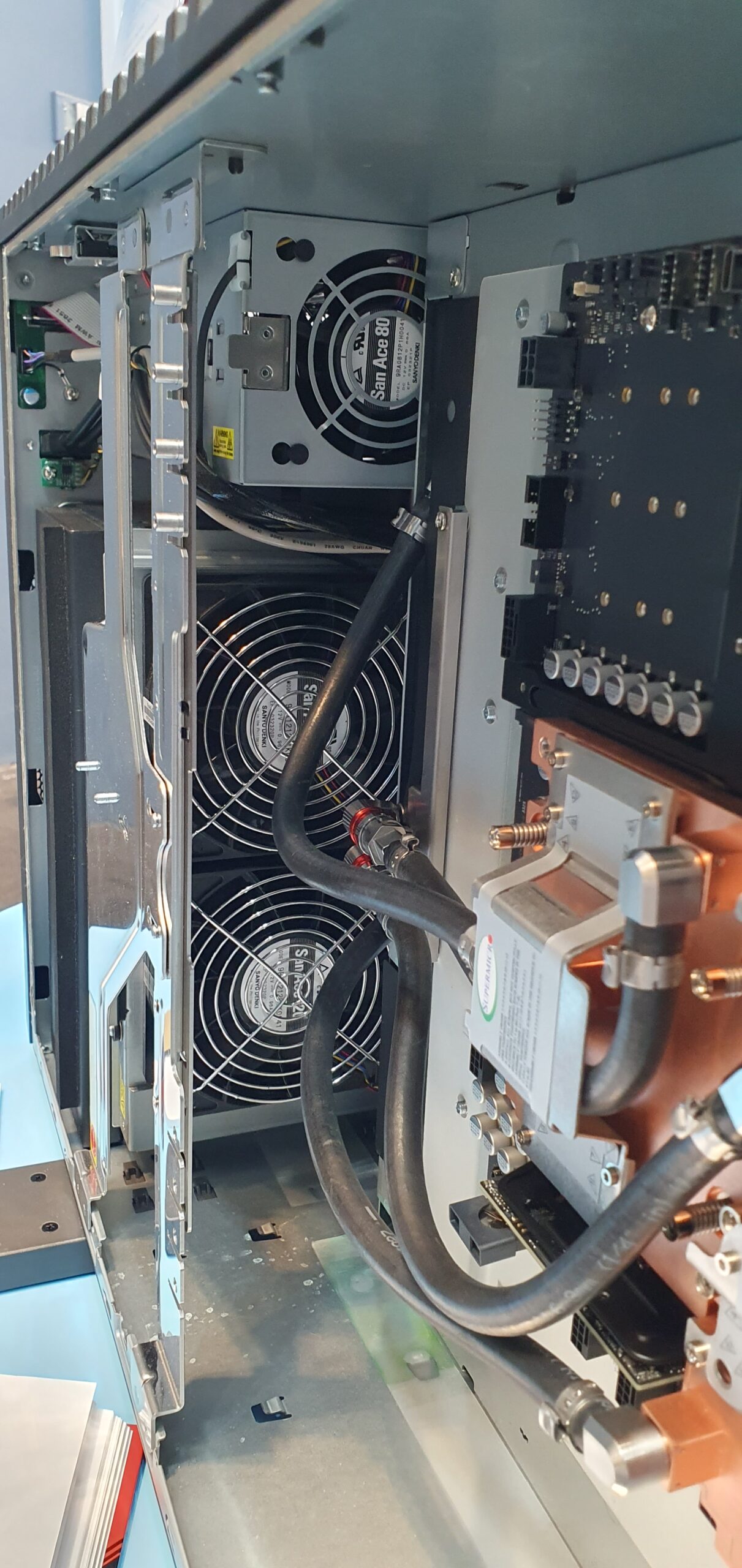 Open workstation chassis showing stacked cooling fans and thick liquid cooling hoses connected to copper cold plates — Supermicro ARS-511GD-NB-LCC NVIDIA DGX Station GB300