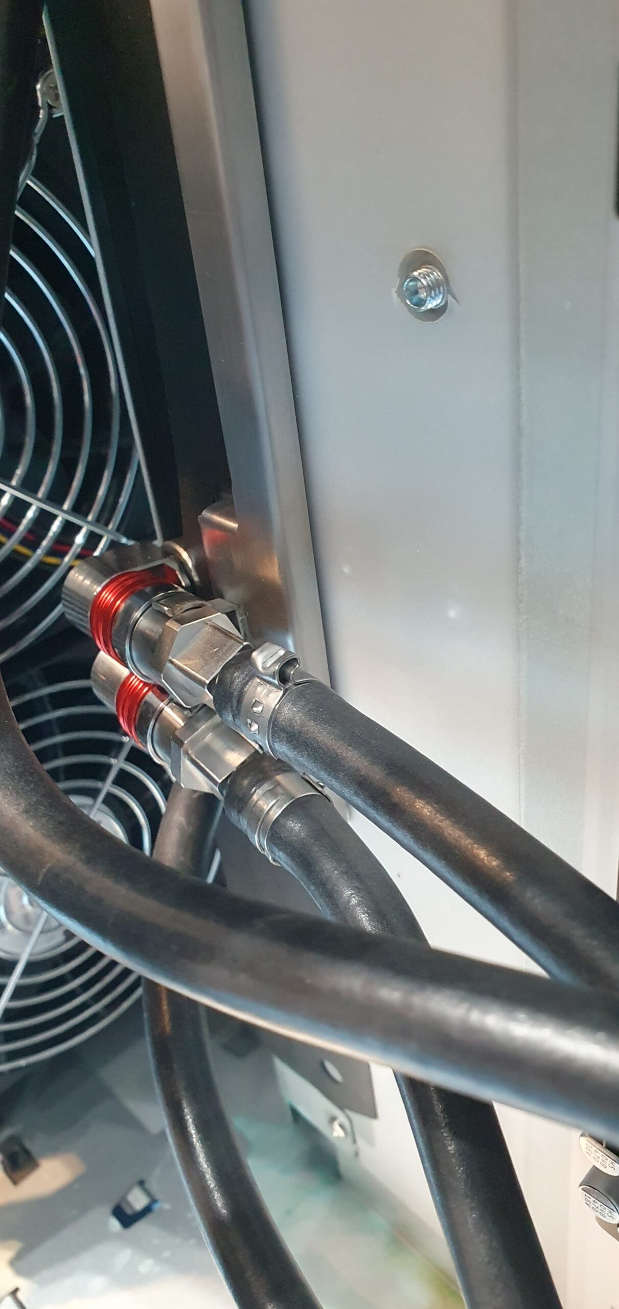 Close-up of quick-disconnect liquid cooling hose fittings inside a workstation chassis with a cooling fan — Supermicro ARS-511GD-NB-LCC NVIDIA DGX Station GB300