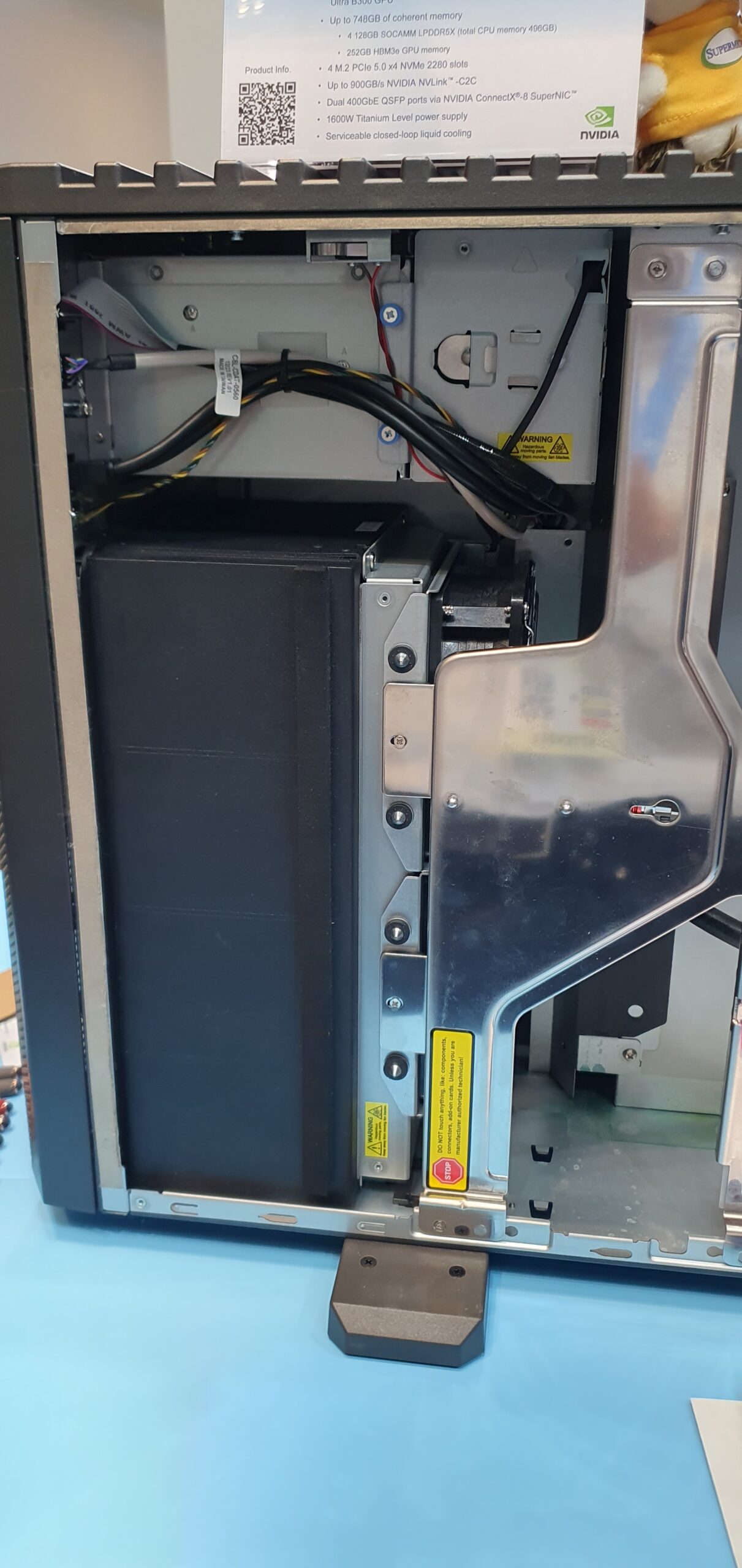 Interior view of an open workstation chassis showing cabling, liquid cooling components, and a spec placard listing memory and… — Supermicro ARS-511GD-NB-LCC NVIDIA DGX Station GB300