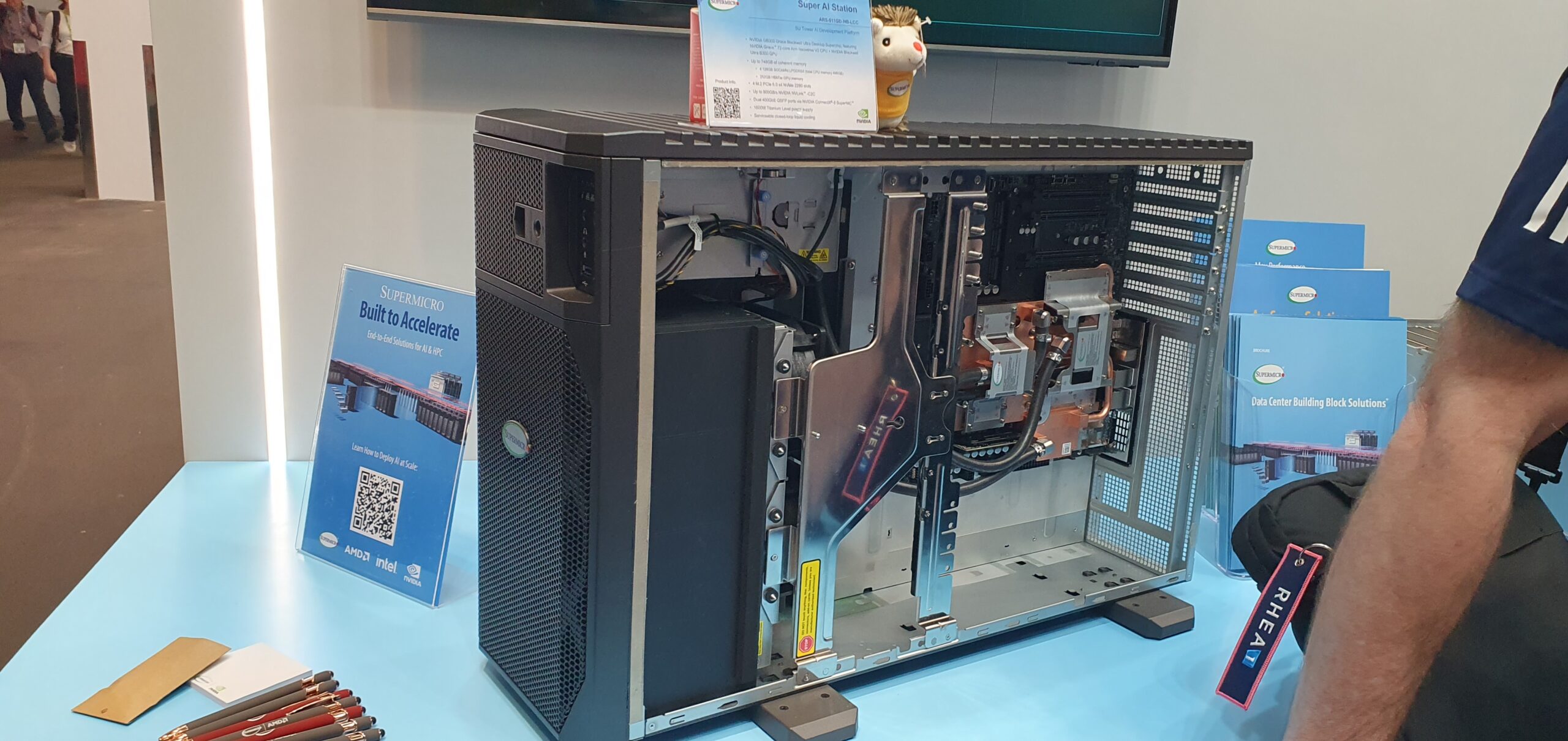 Open tower workstation chassis on display showing internal cooling and cabling at a trade show booth — Supermicro ARS-511GD-NB-LCC NVIDIA DGX Station GB300