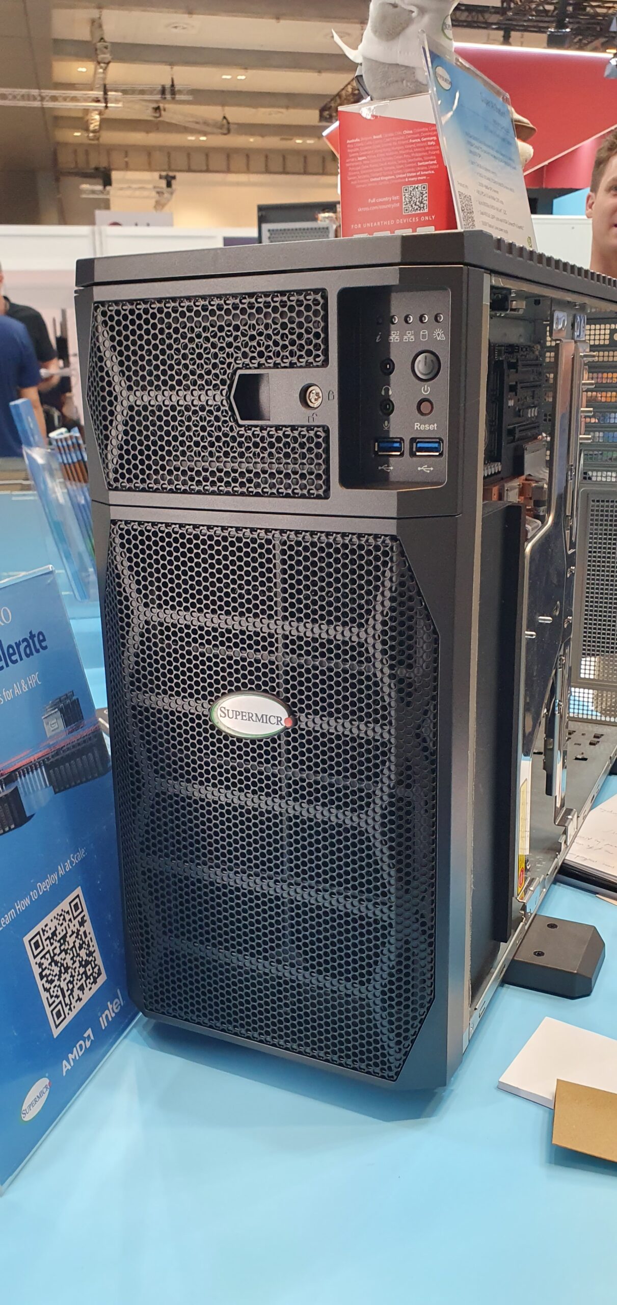 Black Supermicro tower chassis with mesh front panel on display at a trade show booth — Supermicro ARS-511GD-NB-LCC NVIDIA DGX Station GB300
